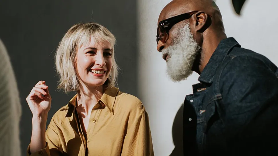A man and woman engage in conversation, facing each other with attentive expressions.