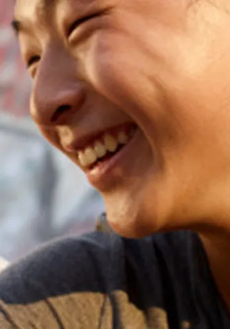 Two young people smiling and laughing in front of a colorful graffiti wall.